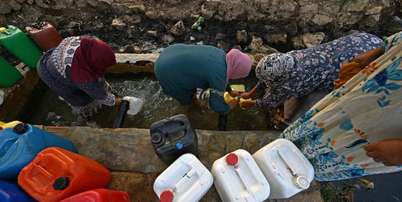 Mulheres recolhem água de fonte nas montanhas de Bizerte, Tunísia, em 21 de julho de 2026. Foto: AFP - FETHI BELAID / RFI