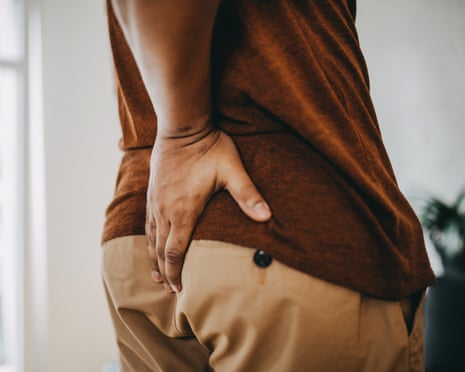 A man puts his hand on his backside in pain.