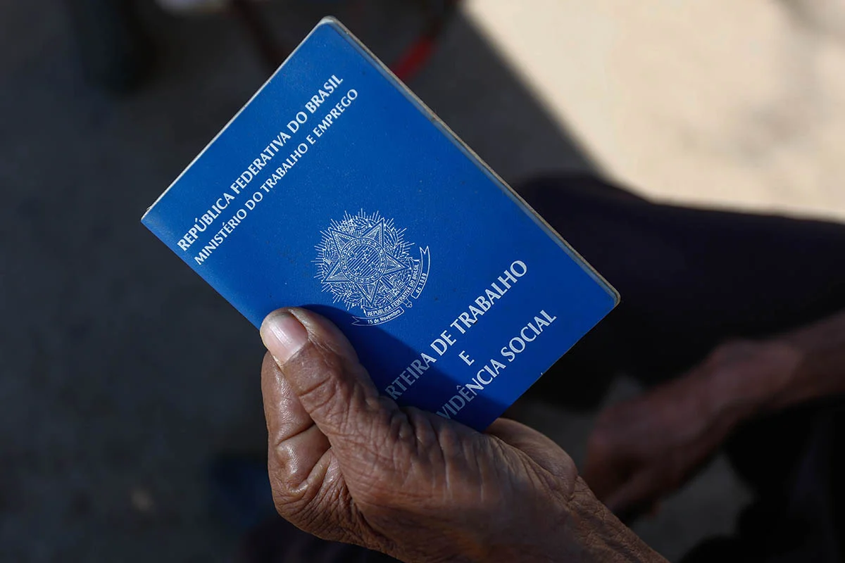 Mão negra segura uma carteira de trabalho
